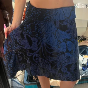 Blå och svart kjol med paljetter - Säljer en blå och svart kortkjol från Odd Molly med unikt mönster och coola paljettdetaljer där det står 'Odd Pub Mall'. Kjolen har en lätt utsvängd form och bred midja, perfekt för dig som gillar statement-plagg.