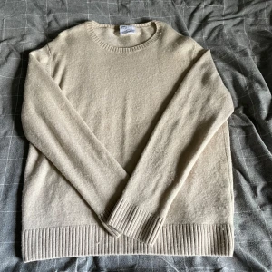 Beige merinoulltröja - Säljer en stilren vaniljvit/beige tröja i 100% merinoull från Colorful Standard. Tröjan har rund hals, ribbade muddar och lång ärm. Perfekt för lager-på-lager och passar till allt. Bra skick, endast lite nopper som tas bort innan köp. Storlek L men bär själv S/M och den passar mig bra i storleken.  Kostar 1199:- ny på care of Carl. Säljer för endast 299:-