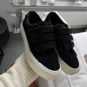 Svarta sneakers i manchester med kardborre - Snygga svarta sneakers i manchestertyg med vit sula och tre breda kardborreband. Knappt använda, max 1 månad eftersom de är för små för stora för mig. Inga defekter! Pris kan diskuteras, nypris 499 säljer för 350