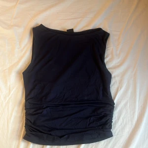 Mörkblå ärmlös topp Gina Tricot - Snygg mörkblå ärmlös topp från Gina Tricot med rund halsringning och lätt rynkade sidor. Tillverkad i mjuk bomullsmix som känns skön mot huden. Perfekt att styla med jeans eller kjol för en clean look. Nypris 199 kr.