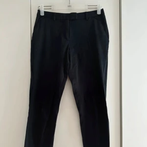 Svarta byxor/chinos - Snygga svarta byxor från H&M med raka ben och klassisk passform. Byxorna har bälteshällor, sidfickor och två bakfickor med lock. Perfekta för en clean och stilren look