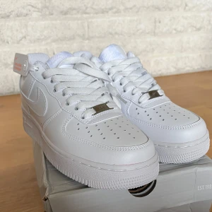 Nike Air Force 1 i storlek 40 - Säljer dessa klassiska Nike Air Force 1 i helvitt skinn med perforerad tå och platt sula. Snygg och tidlös modell med snörning och diskret Nike-logga på sidan och hälen. Aldrig använda på grund av fel storlek, nyskick med lappar och kartong!🤩Nypris runt 1 499kr