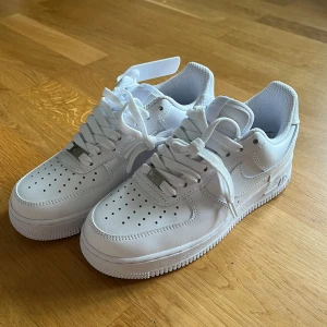 Nike Air Force 1 storlek 37.5 - Säljer dessa klassiska Nike Air Force 1 i helvitt skinn med perforerad tå och platt sula. Snygg och tidlös modell med snörning och diskret Nike-logga på sidan och hälen. Aldrig använda på grund av fel storlek, nyskick med lappar !🤩Nypris runt 1 499kr