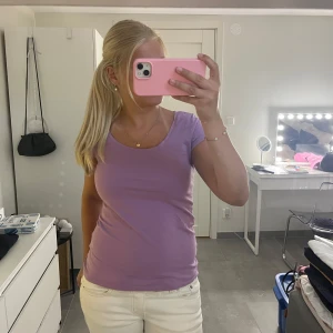 Lila t-shirt från Gina Tricot - En basic lila t-shirt från Gina Tricot med rund halsringning och korta ärmar. Modellen är figurnära och passar perfekt till jeans eller kjol. Tillverkad i mjuk bomull som känns skön mot huden. Enkel och stilren design som är lätt att matcha.
