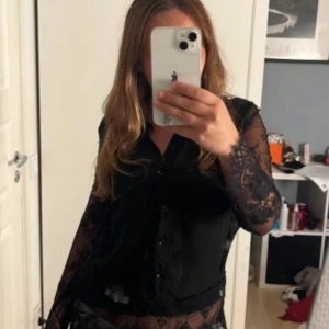 Svart spetsblus från Amisu XS - Supersnygg svart blus från Amisu i storlek XS. Skjortan har transparenta spetsärmar och spetsdetaljer nertill, knappar framtill och en feminin, figurnära passform. Perfekt för dig som vill sticka ut med en elegant och trendig look. Knappt använd, super fin. Pris går att diskutera 💕