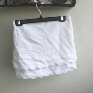 Vit kortkjol med volangkant - Supersöt vit kortkjol i bomull med volangkant nertill och diskret dragkedja i bak. 