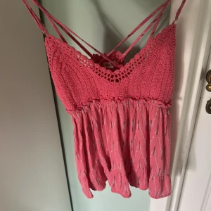 Rosa linnetopp - Supersöt rosa linnetopp från Green Coast med virkade detaljer upptill och tunna axelband som korsas i ryggen💗💗Toppen har en flowy, rynkad nederdel och diskreta mönster i tyget✨           Pris kan diskuteras!