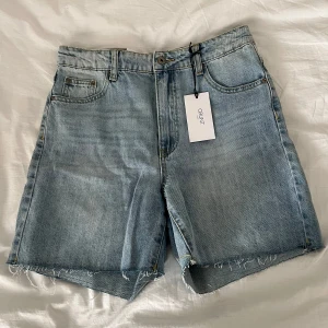 Blå jeansshorts från Grunt - Säljer ett par klassiska blå jeansshorts från Grunt i modellen 90's Shorts Globe Blue. De är oanvända och med lapp kvar! 