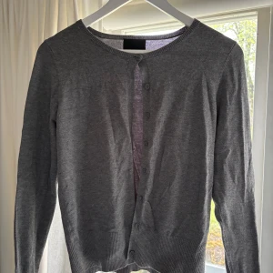 Grå kofta från InWear - Säljer en klassisk grå kofta från InWear i storlek S. Koftan har rund halsringning, långa ärmar och knäppning. 