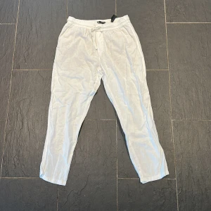 Vita linnebyxor från zara, litet hål - Säljer ett par vita linnebyxor från zara med elastisk midja och dragsko. Byxorna har två fickor bak och är perfekta för varma dagar. Lätta och luftiga med avslappnad passform.