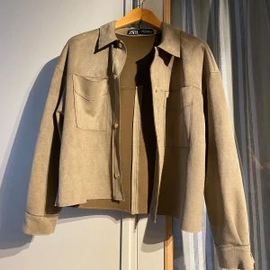 Grön mockaliknande jacka från Zara - Säljer en grön jacka från Zara i mockaliknande material. Jackan har stora bröstfickor, knappar framtill och klassisk krage. Perfekt för lager-på-lager och enkel att styla till olika outfits. Jackan är nästan helt ny, säljer för att den tyvärr är lite för liten på mig💕 nypris 359