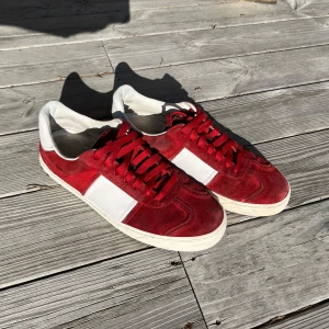 Röda mockasneakers från Valentino Garavani - Säljer ett par röda och vita sneakers från Valentino Garavani. Skorna är i mocka med vita detaljer. Saknas nitar och är lite slitet i hälen men annars är det väldigt bra skick 8/10. Dessa har dessutom slutats sälja och är svåra att hitta speciellt i denna kvalité. Skriv vid minsta fundering!