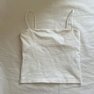 Vit croppad linnetopp - Säljer en enkel och stilren vit croppad linnetopp med tunna axelband. Perfekt för varma dagar och lätt att matcha med olika outfits.