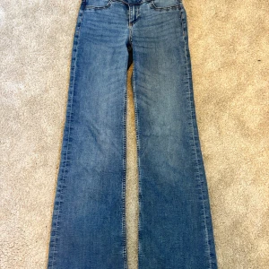 Blå bootcut jeans - Säljer ett par klassiska blå bootcut jeans med normal passform och medellåg midja. Perfekta för dig som gillar en retroinspirerad look med utsvängda ben. PRIS GÅR ATT DISKUTERA!!