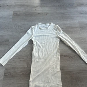 Vit ribbad långärmad topp från SHEIN - Säljer en vit, ribbad långärmad topp från SHEIN i storlek XS. Toppen har en tight passform och är tillverkad i ett mjukt, stretchigt material. Perfekt att styla med jeans eller kjol för en clean look.