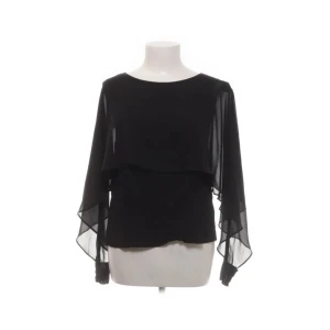 Svart blus med transparenta ärmar från Zara Woman - Säljer en svart blus från Zara Woman med långa, transparenta ärmar i chiffongliknande material. Blusen har ett lager över bysten som ger en snygg detalj och flowig känsla. Perfekt för dig som gillar stilrena och eleganta plagg.