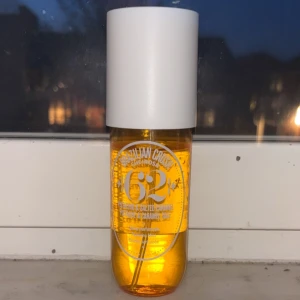 Sol de Janeiro Brazilian Crush Cheirosa 62 Body Fragrance Mist - En kroppsmist från Sol de Janeiro med doften Cheirosa 62. Flaskan är genomskinlig och orange med vit spraykork och lock. Innehåller 240 ml och ger en tropisk, varm doft med inslag av pistage och salt karamell.