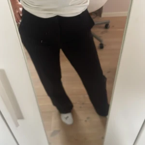 Svarta kostymbyxor med raka ben - Snygga svarta kostymbyxor med normal passform, medelhög midja och raka ben. Byxorna har klassisk design med fickor framtill och passar perfekt till en stilren look.