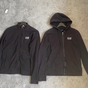 Svarta EA7 ziptröjor - (BÅDA FÖR 500 )Två svarta ziptröjor från EA7. Ena modellen har huva och dragsko, den andra är utan huva. Båda har EA7-logga på bröstet och vita ränder på  stilren look. Stolen S och är i väldigt bra skick inga skador .