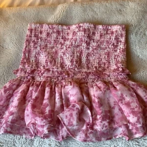 Rosa blommig volangkjol - Supersöt rosa kjol med blommigt mönster och volangdetaljer. Perfekt till sommaren!💖