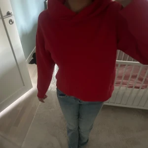 SVINSNYGG Röd hoodie med croppad passform - Säljer en röd hoodie med croppad passform och långa ärmar. Tröjan har en mysig huva och är perfekt för en avslappnad stil. Passar dig som gillar en enkel men färgstark look.