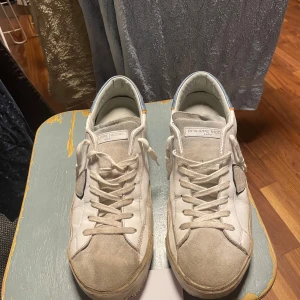 Vita sneakers från Philippe Model - Säljer ett par vita Philippe Model sneakers med grå och blå detaljer. Slitningar vid hälen, men inget man ser eller känner, skick 7/10. Boxen och tags medföljer, och priset är inte skrivet i sten, så kom gärna med prisförslag! 