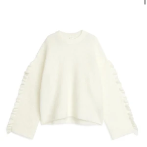 Vit stickad tröja med volangdetaljer - Superfin vit stickad tröja med volangdetaljer längs ärmarna. Tröjan har en avslappnad passform och långa ärmar. Helt slutsåld  🫰🫰🫰