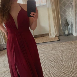 Vinröd långklänning, nyskick! - Säljer en vinröd långklänning som är helt oanvänd! Mäter 105 cm i längd från midjan neråt.Passar mig som vanligtvis har Small. Köpt för 3000:-