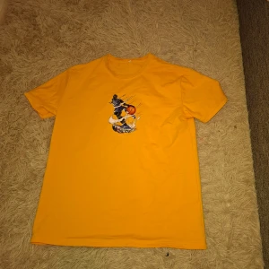 Gul Nike t-shirt med baskettryck - Säljer en gul Nike t-shirt med ett coolt tryck av en basketspelare med basketboll på bröstet. T-shirten har rund hals och är kortärmad. Materialet är en mix av bomull, polyester och spandex vilket gör den mjuk och stretchig.