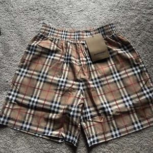 Beige rutiga shorts från Burberry - Snygga shorts från Burberry i klassiskt beige rutigt mönster med elastisk midja och innerfoder i mesh. Perfekta för sommaren och har en avslappnad passform. Ikonisk design som sticker ut.