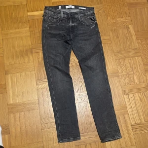 Svarta jeansbyxor Replay Anbass slim fit  - Säljer ett par svarta Replay Anbass jeans med fem fickor och snygga kontrastsömmar. Byxorna har normal passform och klassisk knappgylf. Perfekta för dig som gillar stilrena och bekväma jeans.
