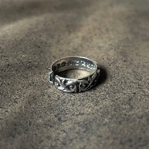 Rockstar Eternal Vine Ring - En ring med vinranka-motiv som slingrar sig runt hela bandet, vilket skapar en organisk och kraftfull design. Inskrifter på insidan ger en personlig touch. Storlek 8.5, justerbar för en perfekt passform. Ett stilfullt smycke för den som vill ha både natur och attityd i sin look.