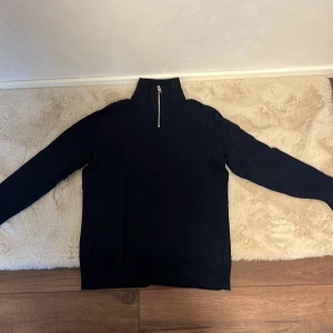 Mörkblå långärmad tröja med dragkedja - Säljer en stilren mörkblå långärmad tröja från Jack & Jones. Tröjan har en halv dragkedja vid halsen och är tillverkad i ett mjukt material.