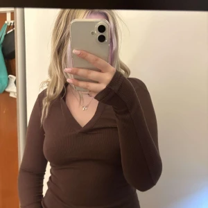 Brun ribbad långärmad topp från Gina Tricot - Säljer en brun ribbad långärmad topp från Gina Tricot med v-ringning. Snygg och enkel modell som sitter tight och passar perfekt till jeans eller kjol. Supermjuk och skön att ha på sig!