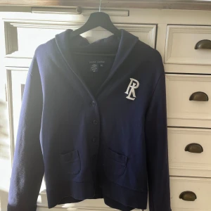 Mörkblå kofta från Ralph Lauren - Säljer en stilren mörkblå kofta/cardigan från Ralph Lauren. Storlek Barn XL så sitter som en S. Tröjan är i toppskick. Skriv för pris och mer info eller bilder!