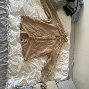 Beige skjorta med knappar - Säljer en beige skjorta med långa ärmar och knappar framtill. Skjortan har klassisk krage och är tillverkad i ett lätt material som passar perfekt till många olika outfits.