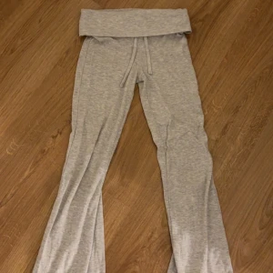 Grå mjukisbyxor från Gina Tricot - Grå mjukisbyxor från Gina Tricot med utsvängda ben och bred, vikbar midja med dragsko. De är lowaist och bootcut. De har inga fläckar eller hål. De är endast använda 3 gånger. De är storlek 134 men de sitter som xxs