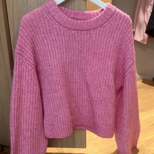 Rosa stickad tröja från Gina Tricot - Supermjuk och mysig rosa stickad tröja från Gina Tricot. Tröjan har en croppad passform, bred ribbad mudd vid ärmslut och halsringning samt långa ärmar. Perfekt färg för en sommarkväll😍