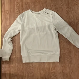 Vit sweatshirt från Sail Racing - Säljer en stilren vit sweatshirt från Sail Racing i storlek S. Tröjan har rund halsringning och långa ärmar, perfekt för en clean och enkel look. Mjuk och skön bomullskänsla, passar till det mesta i garderoben.