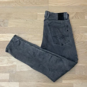 Replay Jeans - Säljer ett par grå jeansbyxor från Replay, modell Anbass. Storleken är L30 W31. Snygg slitning på högra knät. Inga synliga defekter. Priset är förhandlingsbart hör av dig om du undrar de minsta 🙌