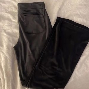 Svarta mjukisbyxor från gina - Svarta mjukisbyxor i mjukt material med en stor ficka bak. Byxorna har raka ben, perfekta för en chill och avslappnad stil. Snygga att matcha med en hoodie eller crop top. Snöret är borta men annars inga defekter.