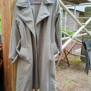 Grå kappa från Bik Bok i ullmix XS - Snygg grå kappa från Bik Bok i storlek XS. Oversized känsla med bred krage, stora fickor och bälte i midjan. Tillverkad i en mjuk ull- och polyestermix med återvunnen ull. Perfekt för höst och vinter när du vill vara både varm och stilren.