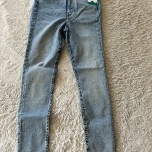 Super skinny jeans från H&M - Ljusblå super skinny jeans från H&M med hög midja och ankellängd. Klassisk femficksmodell i stretchigt denim som sitter tight hela vägen ner. 