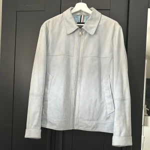Ljusgrå mockajacka från BOSS - Ljusblå mocka jacka från Hugo Boss. originalpris ca 5700 kr. Lite fläckar vid kragen. Har tyvärr inte kvittot för att jag fick den i julklapp. Passar mig bra, 187 cm/ 78 kg