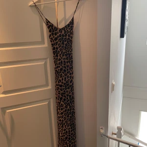 Leopardmönstrad långklänning Gina Tricot - Säljer en långklänning från Gina Tricot med leopardmönster. Klänningen har tunna axelband och v-ringad halsringning. Färgerna går i beige och svart, och materialet känns lätt och följsamt. Perfekt för dig som vill sticka ut med en trendig look.