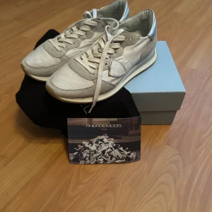 Philippe Model vita sneakers med silverdetaljer - Tja säljer dessa riktigt feta Philips model skor till ett riktigt bra pris kartong och dustbag följer inte med  i köp och skicket är mycket bra nypris runt 3000 mitt pris 1399 hör av er om ni är intresserade storlek 40 men sitter mer som 41 