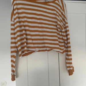 Randig långärmad tröja från H&M Divided - Säljer en oversized långärmad tröja från H&M Divided i storlek L. Tröjan har vita och rostbruna horisontella ränder, rund halsringning och avslappnad passform. Perfekt för en chill och trendig look. Materialet är mjukt och skönt, troligtvis bomull.