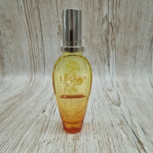 Escada Taj Sunset Eau de Toilette 50ml - Fräsch och tropisk parfym från Escada, Taj Sunset, i en snygg glasflaska som skiftar från gult till orange. Flaskan har silverfärgad metallkork och dekorativa detaljer på framsidan. Innehåller 50 ml Eau de Toilette.