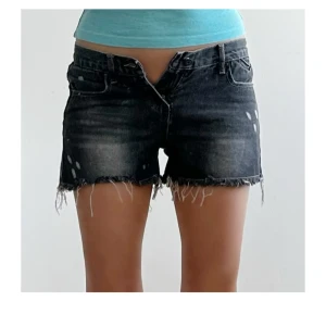 Svarta jeansshorts med fransig kant - Snygga svarta jeansshorts med slitna detaljer och fransig kant nertill. Lågmidjade modell med klassiska fickor och bälteshällor. Perfekta för en avslappnad och cool stil i sommar.
