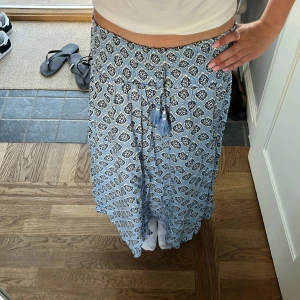 Blåvit långkjol med mönster och tofsar - Superskön långkjol i blått och vitt med snyggt grafiskt design. Säljer pga inte passar längre. Pris kan diskuteras 💕